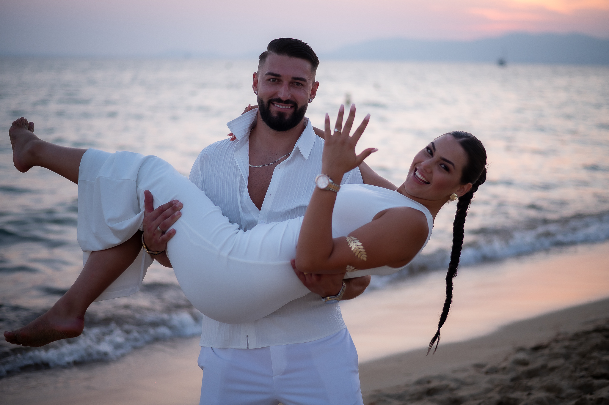 hombre cogiendo a su prometida en brazos en la playa