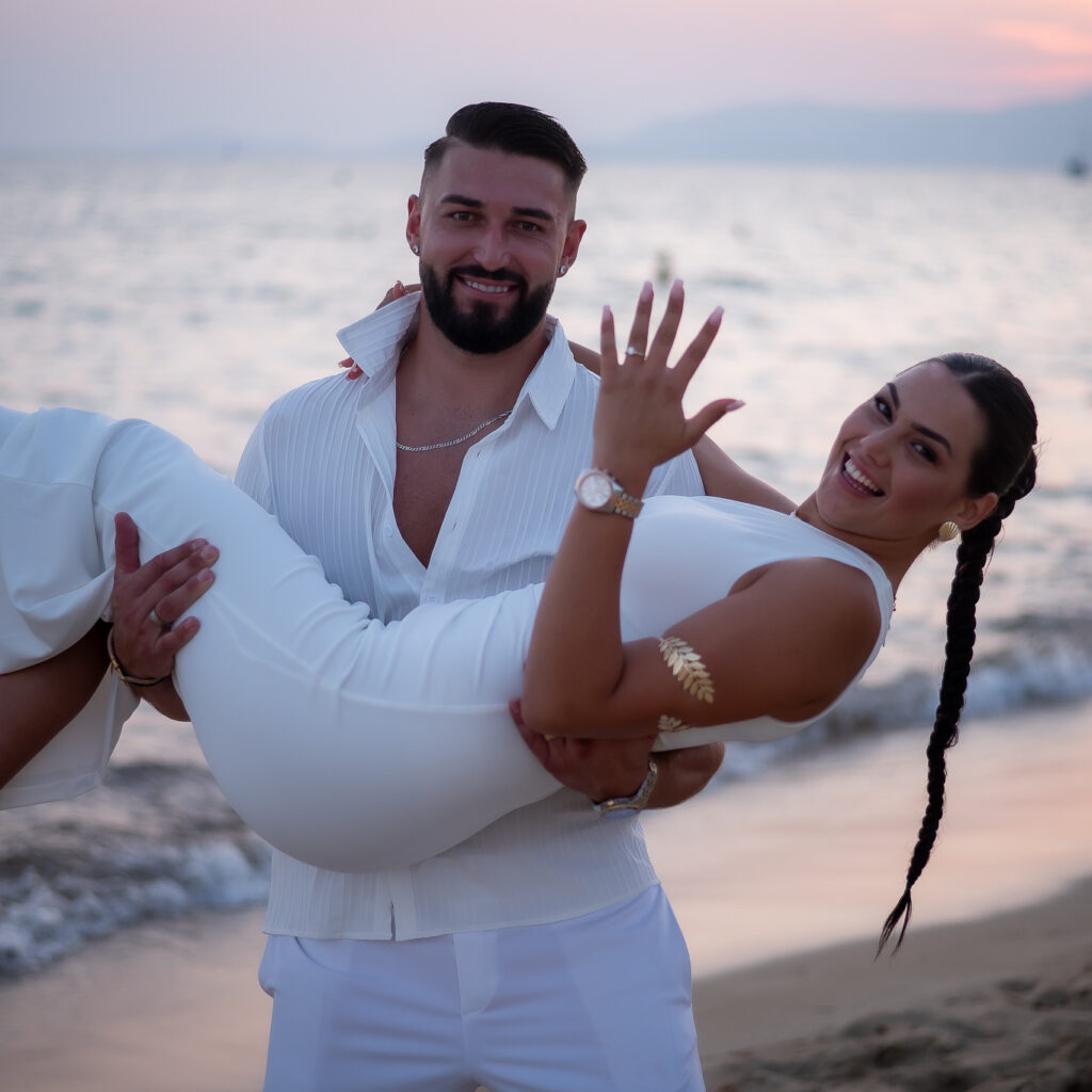 hombre cogiendo a su prometida en brazos en la playa